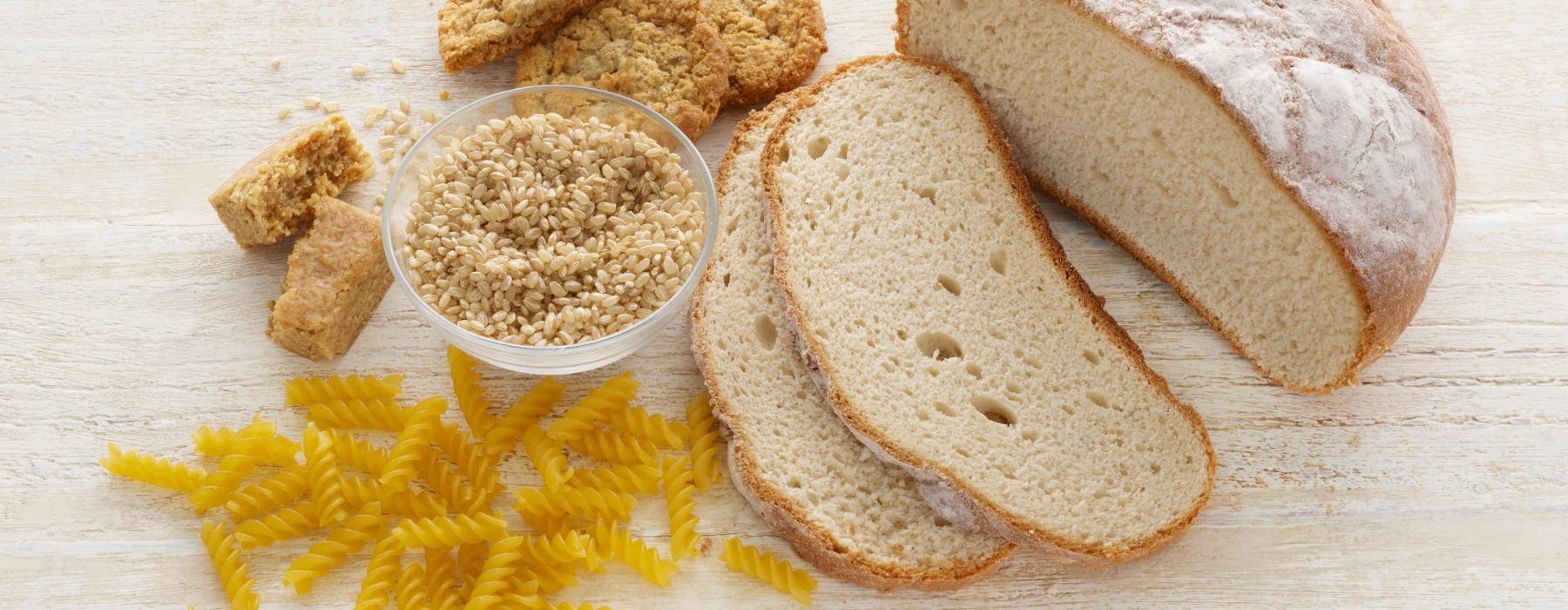 Pão, massas, cookies e grãos de trigo sobre a mesa, alimentos com glúten que devem ser evitados por pessoas com doença celíaca.
