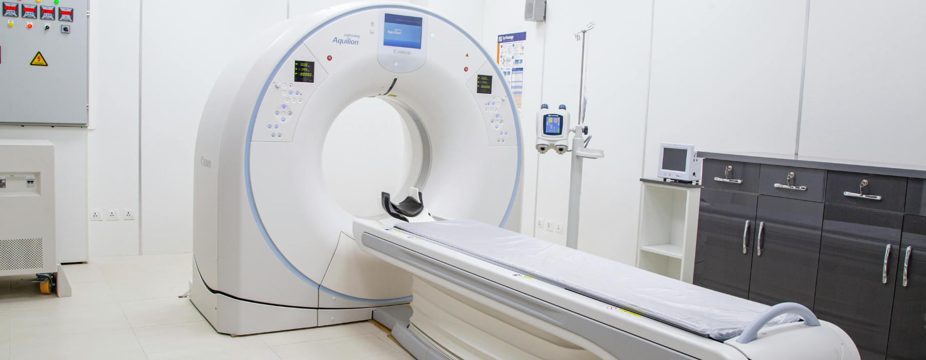 Equipamento de tomografia computadorizada em sala hospitalar, usado em exames de imagem.