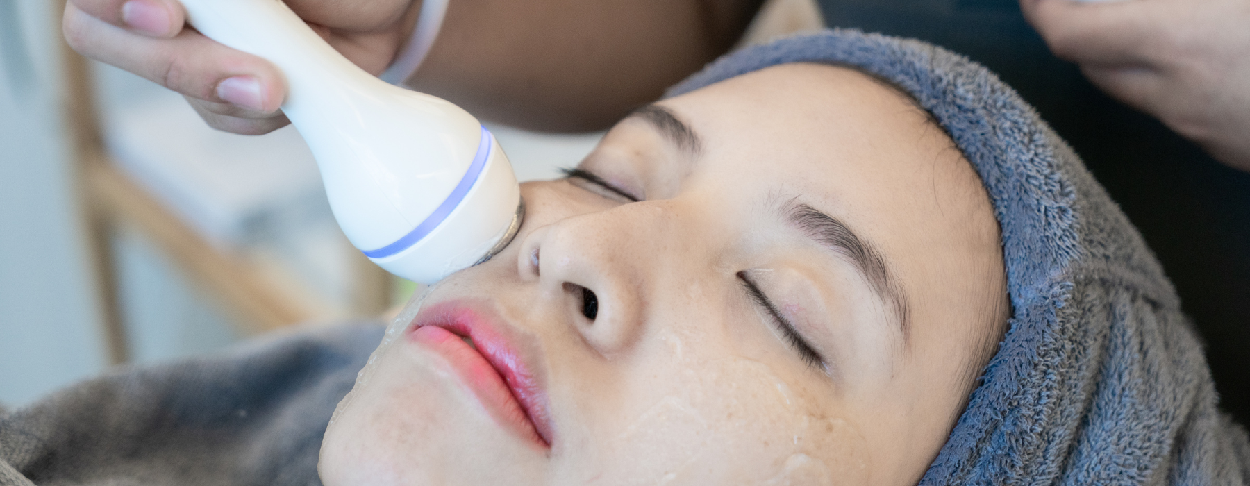 Profissional utilizando aparelho sobre o rosto de uma pessoa para exame complementar da pele, auxiliando na avaliação de possíveis alterações associadas ao câncer de pele.