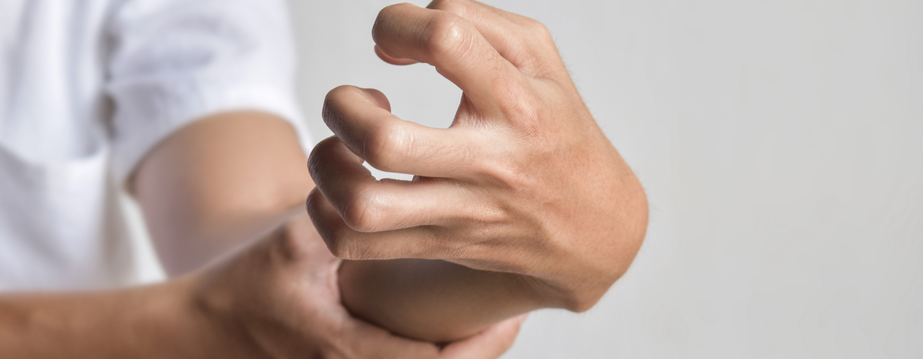 Mão com dedos rígidos e contraídos, representando movimentos involuntários ou espasmos musculares.